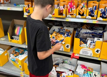 Young boy looks at school supplies in a store while back-to-school shopping.