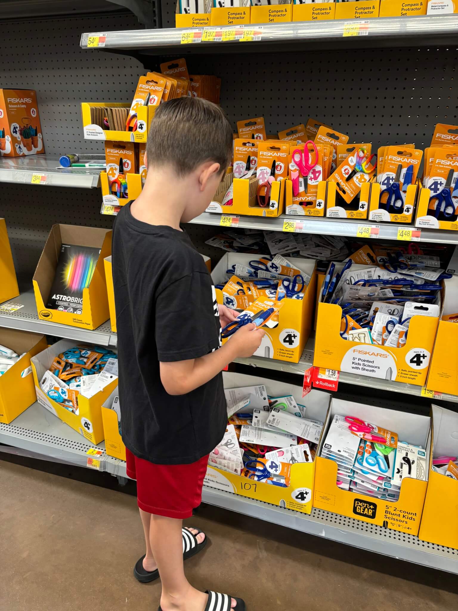 Young boy looks at school supplies in a store while back-to-school shopping.