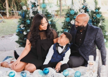 Toni Glaze, founder and president of family fashion brand Toni by Toni, gazes down at her son as her husband smiles at her in front of two Christmas trees decorated in blue and white.
