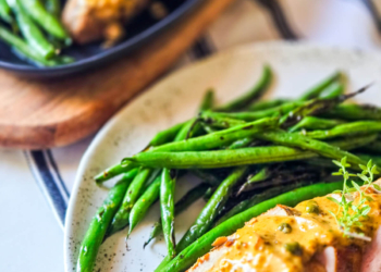 Holiday recipe Pork Tenderloin with a Creamy Mustard Sauce plated next to Seared Haricot Verts on a linen tablecloth.
