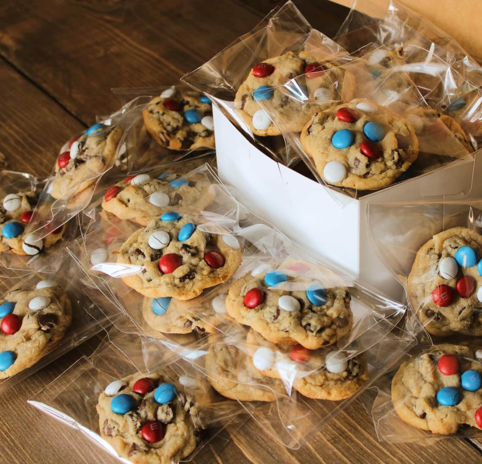 Multiple packaged M&M cookies spilling out of a white box from Operation Cookies, LLC, a military-owned small business.
