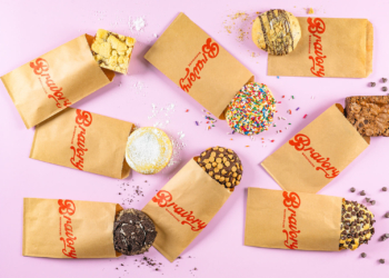 Variety of chocolate, sprinkle, and chocolate chip baked goods from Bravory Bakehouse, a military-owned small business, on a pink background.