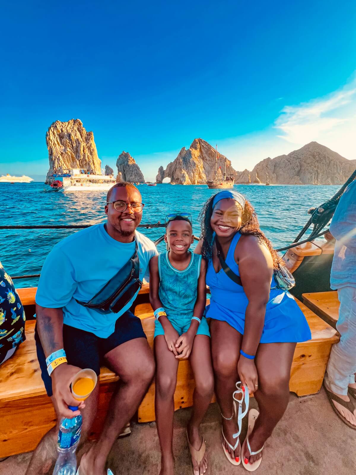 Military family smiling on a boat excursion on bright blue water while on vacation in Mexico.