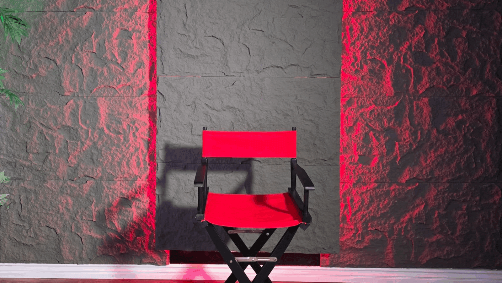 An empty red director's chair in front of a gray wall. 