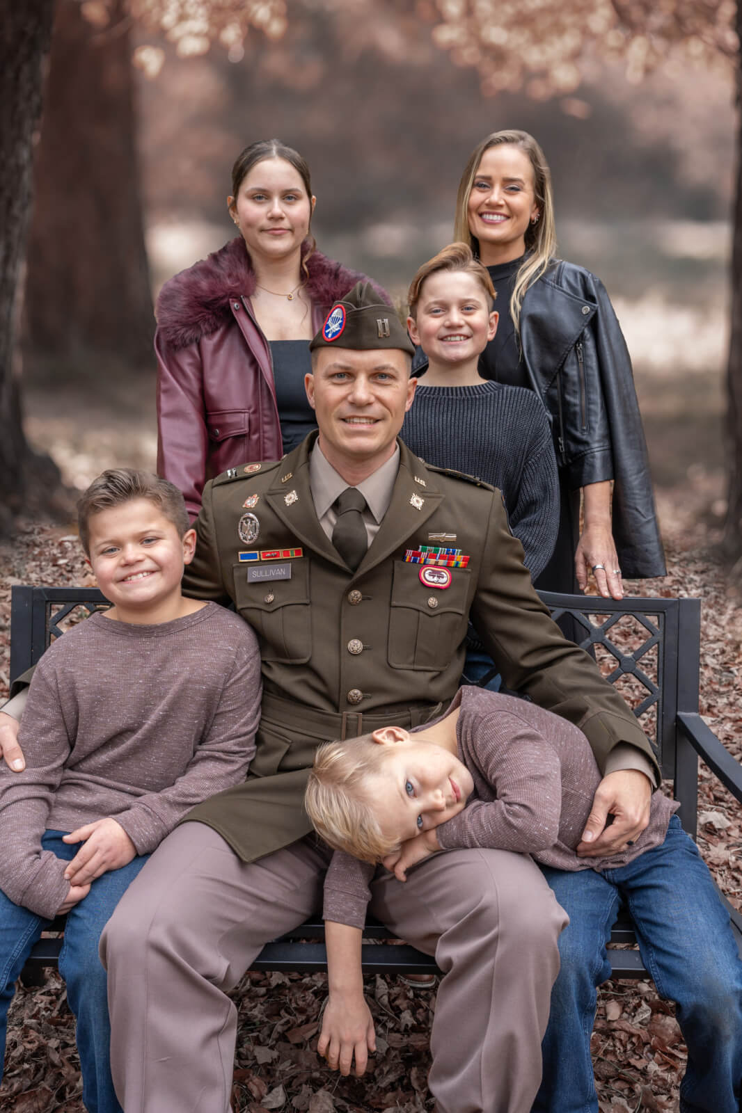The Sullivan family, with father Peter in his Army uniform sitting with two of their boys, and Ashlee of WOMAN + WARRIOR standing behind with their daughter and another son.