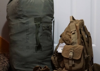 Army boots and rucksacks lean against a door in preparation for a service member's deployment.